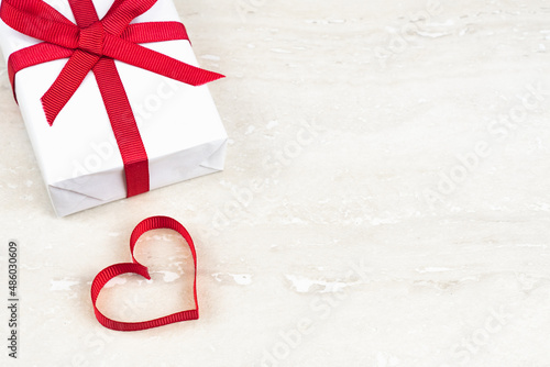 Valentine's Day, birthday concept with copy space. Red ribbon heart and gift box on light background photo