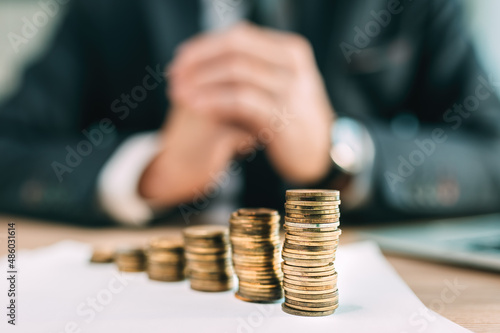 Retirement saving plant concept, businessman with coin stack on office desk