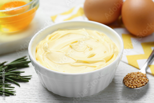Delicious homemade mayonnaise with ingredients on white wooden table, closeup