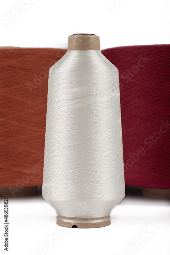 Spool of sewing thread, isolated on white background. Colored yarns used by factories in the clothing industry. Threads wound on the spool. Colored reels