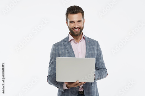 Businessman holding laptop and looking at camera