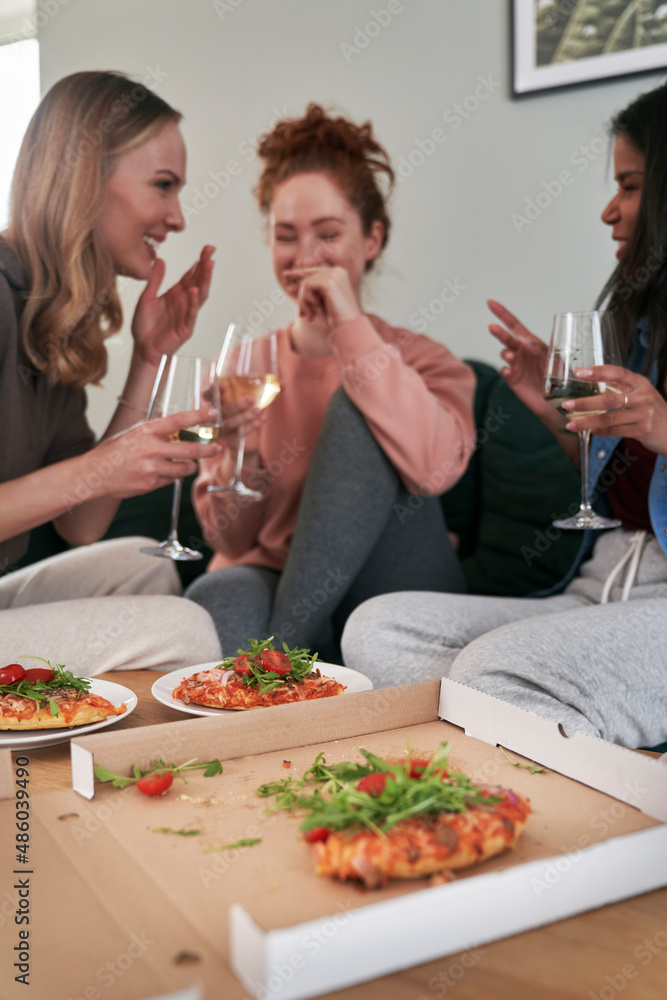 Caucasian female friends eating pizza at home and having fun