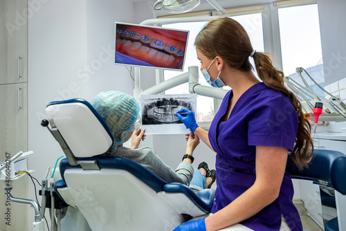 A professional dentist shows the patient pictures of his jaw and teeth.