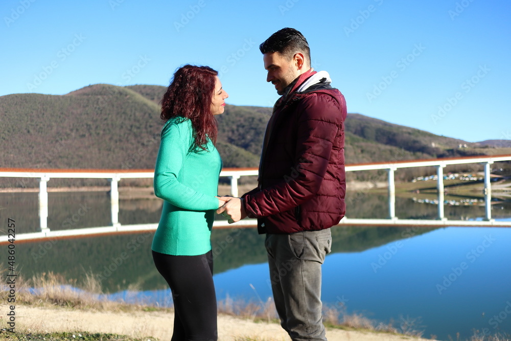 young caucasian couple looks at each other by the lake, romantic scene, love concept young caucasian couple looks at each other by the lake, romantic scene, love concept