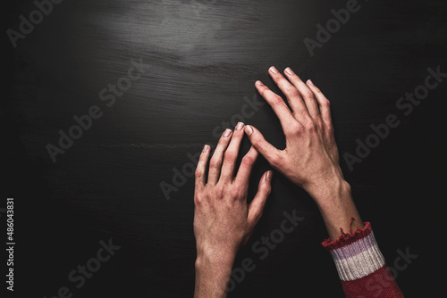 Poverty and hunger - dirty skinny child’s hands on black background, copy space