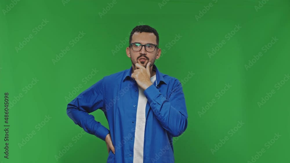 Pensive young bearded man looking for solutions to problems over green background isolated Pensive young bearded man looking for solutions to problems over green background isolated