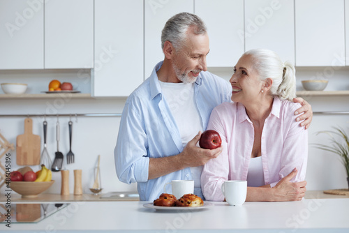 Man hug wife and give apple to her at kitchen
