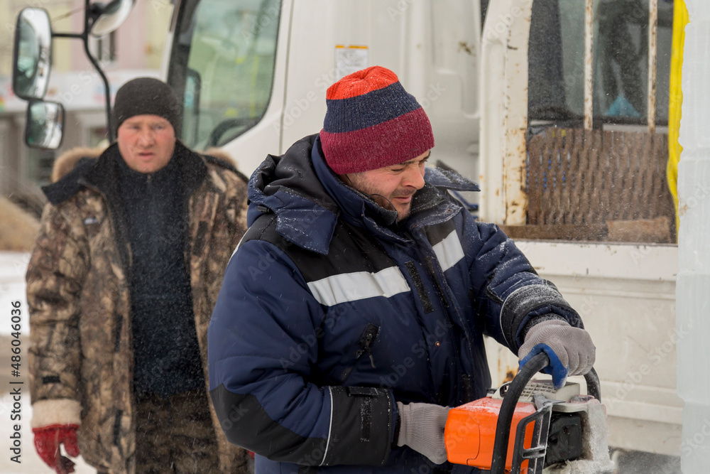 Fototapeta premium Worker cuts ice panel with gasoline saw