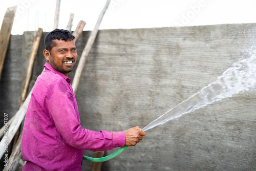 Quadro em tela happy Construction labour curing brick cement wall by using water to avoid cracks and increase the strength of wall by looking at camera - concpt of building renovation and maintenance