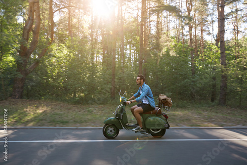 Man riding scooter on asphalt road in sunny forest © Drobot Dean
