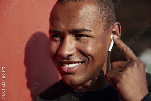 Smiling black man listening music in earphones