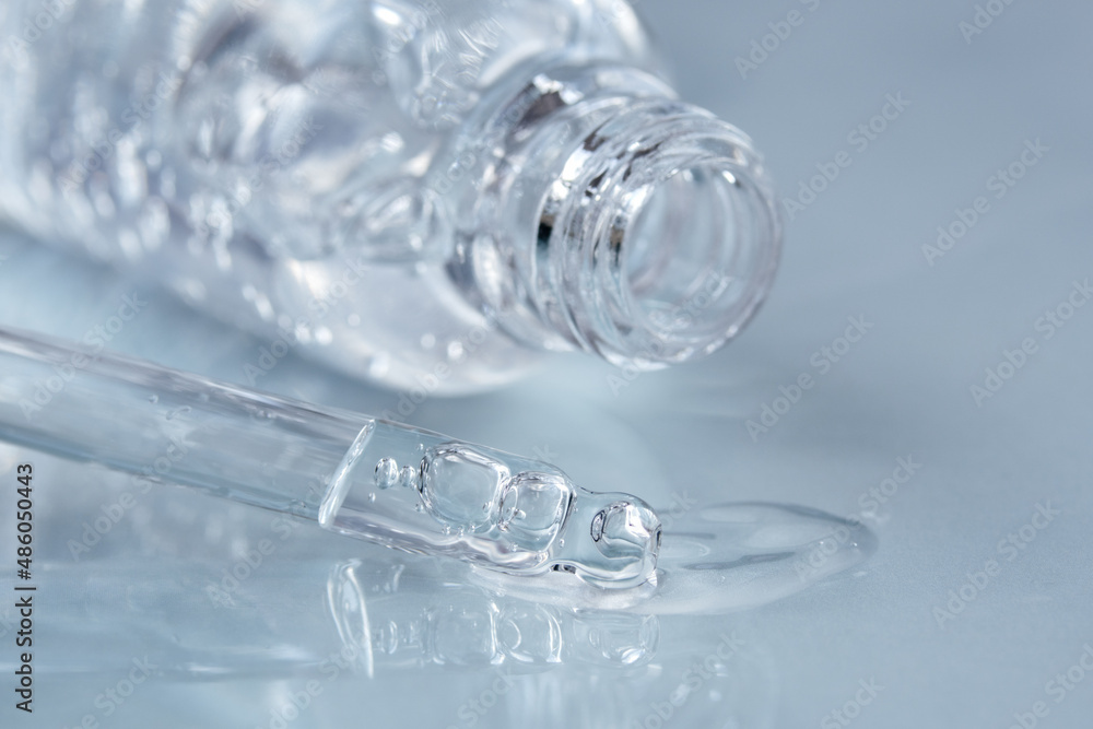 Pipette with fluid hyaluronic acid and opened bottle on blue background. Cosmetics and healthcare concept closeup. Dose of serum, retinol with air bubbles. Flat lay. Luxury beauty product presentation Pipette with fluid hyaluronic acid and opened bottle on blue background. Cosmetics and healthcare concept closeup. Dose of serum, retinol with air bubbles. Flat lay. Luxury beauty product presentation