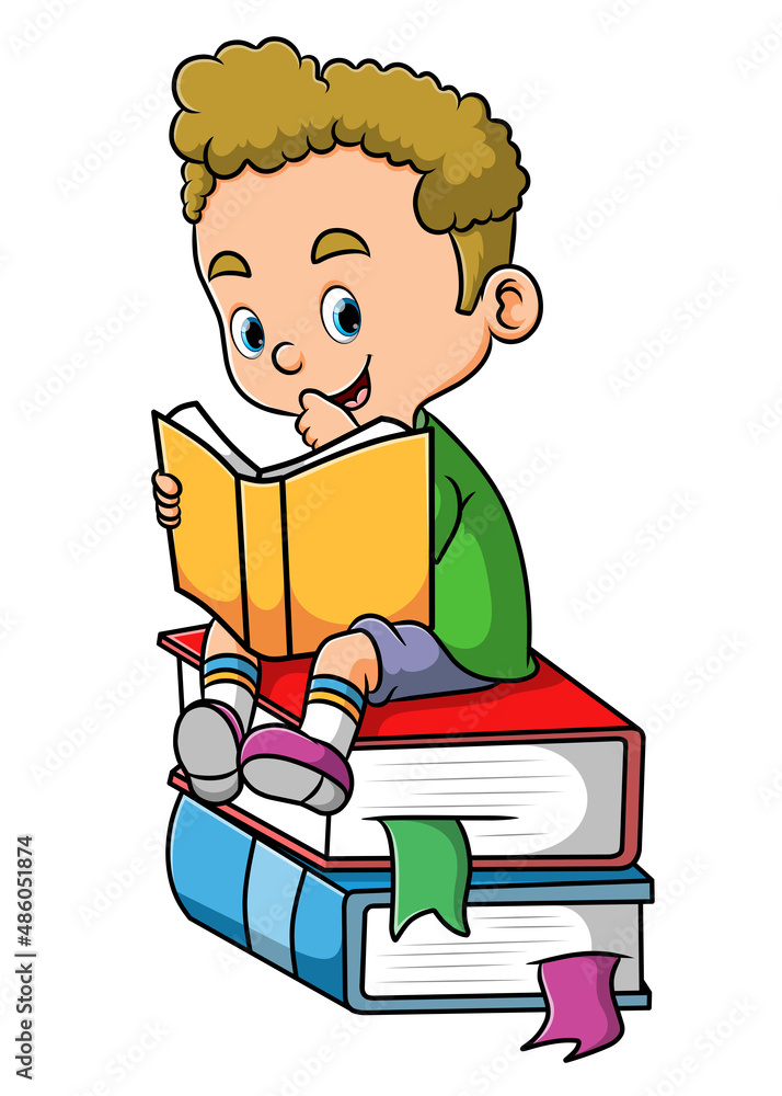 The cute boy is reading the book and sitting on the books The cute boy is reading the book and sitting on the books