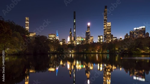 Central Park Lake with view of New York City Billionaire's Row from dusk to night. Timelapse citiscape of luxury apartment skyscrapers