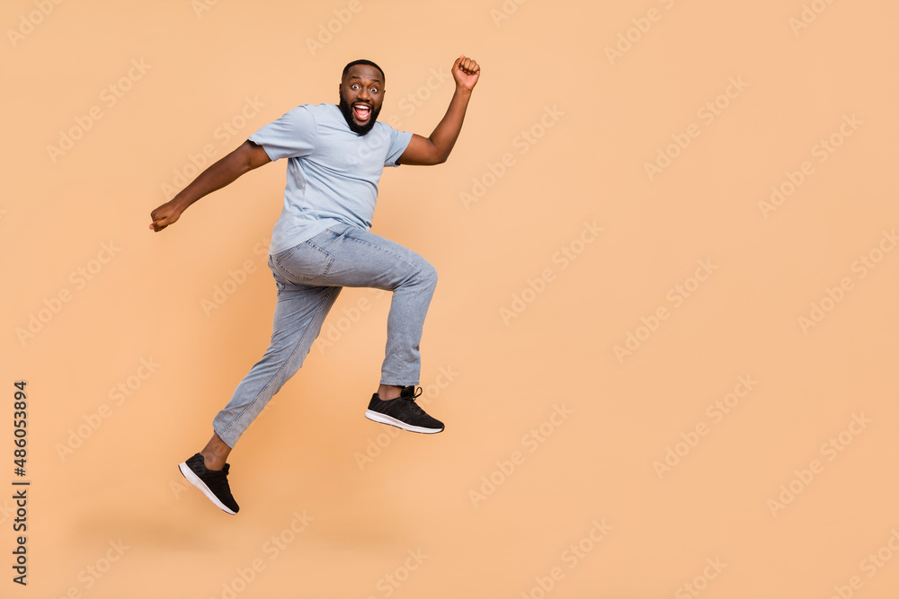 Fototapeta premium Full length body size view of attractive cheerful sportive guy jumping striving isolated over beige pastel color background