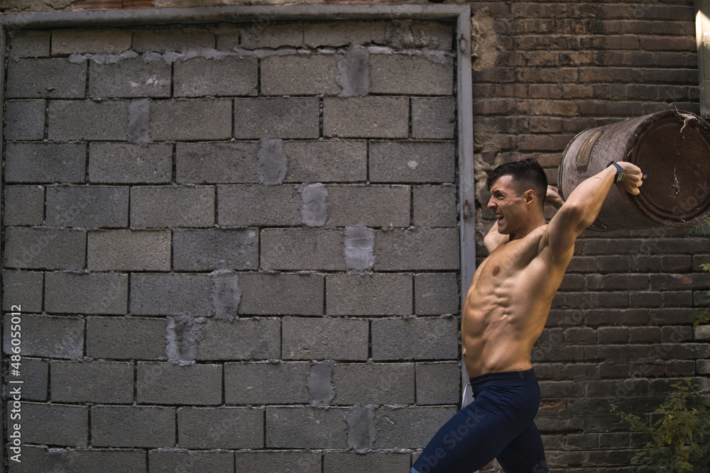 Muscular shirtless man throwing bin.