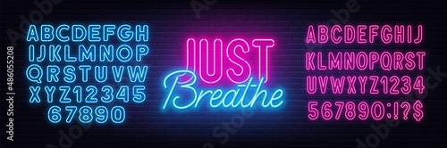 Just Breathe neon lettering on brick wall background.