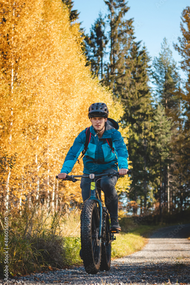 Fototapeta premium Recreational cyclist rides through the Vuokatti arena in beautiful autumn weather and at sunset. Exploring the area on fat bikes. Finnish landscape
