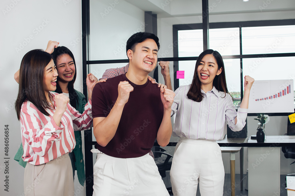 Obraz premium Asian young business man and his colleagues wearing casual shirt is smiling and very happy with his success in office. Working, Teamwork and Leadership Concept.
