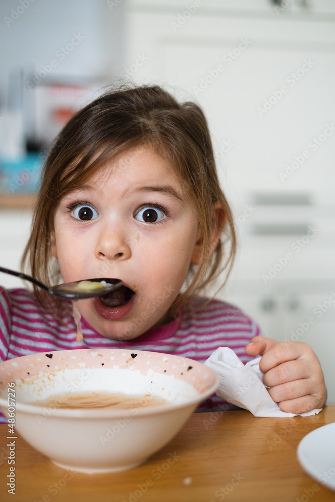 Close up of preschool girl portrait with funny expression eating soup at home Close up of preschool girl portrait with funny expression eating soup at home