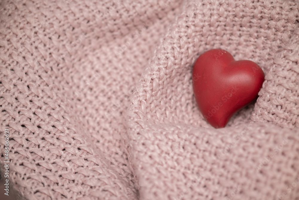 Red heart on a knitted pink textile texture. Valentine's day background