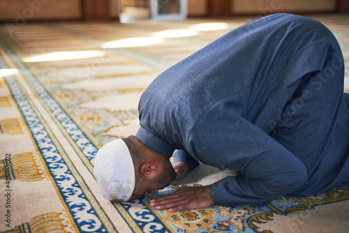 Photos Young muslim man touches his forehead to the ground prostrate during prayers in