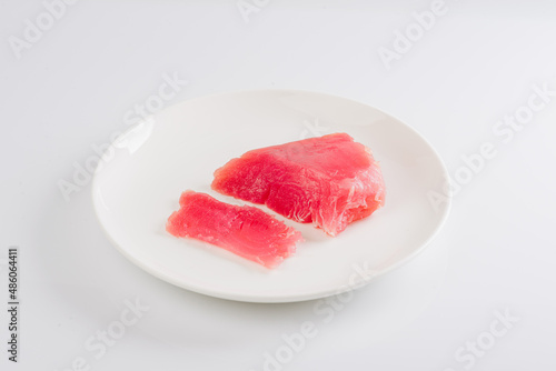 a piece of fresh tuna on a white plate on a white background