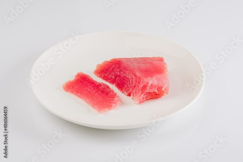 a piece of fresh tuna on a white plate on a white background