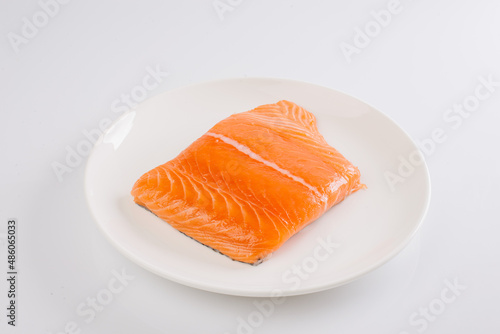 raw salmon fillet on a white plate on a white background