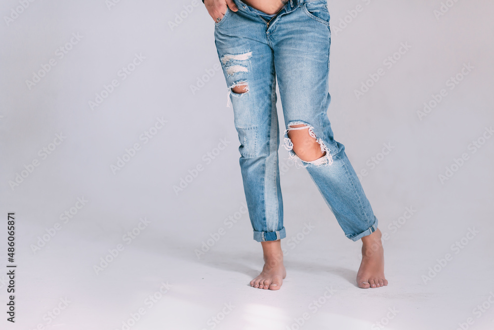 the legs of a pregnant woman in torn jeans in the studio at the cyclorama