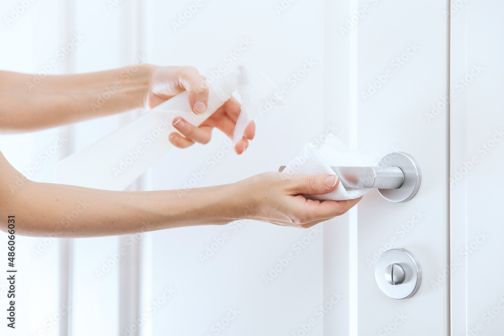 Cleaning white door handles with an antiseptic wet wipe and sanitizer spray. Disinfection in hospital and public spaces against corona virus. Woman hand using towel for cleaning home room door link. Cleaning white door handles with an antiseptic wet wipe and sanitizer spray. Disinfection in hospital and public spaces against corona virus. Woman hand using towel for cleaning home room door link.