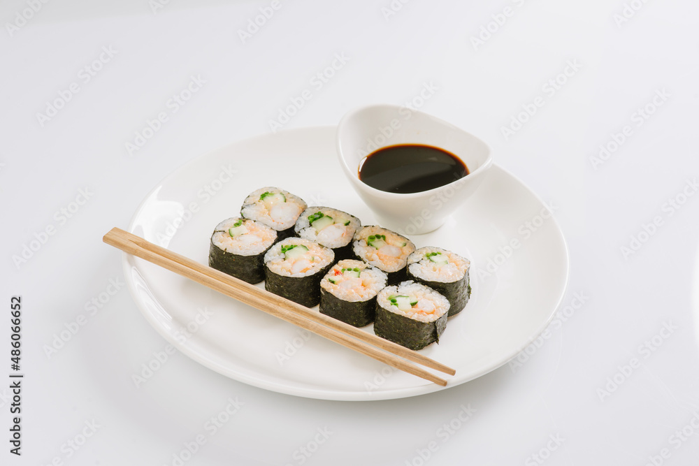 Sushi with chopsticks on a white plate. Sushi roll japanese food in restaurant isolated on white background. Fresh hosomaki pieces with rice and nori. Sushi with chopsticks on a white plate. Sushi roll japanese food in restaurant isolated on white background. Fresh hosomaki pieces with rice and nori.