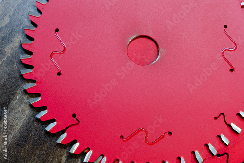 Two red spare blades for circular saw on wooden surface, furniture manufacturing, selective focus photo