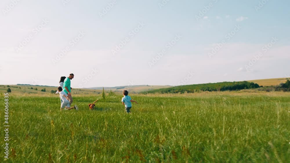 In a perfect evening beautiful family with two cute kids enjoy the time at nature together with their cute small dog they running all together In a perfect evening beautiful family with two cute kids enjoy the time at nature together with their cute small dog they running all together