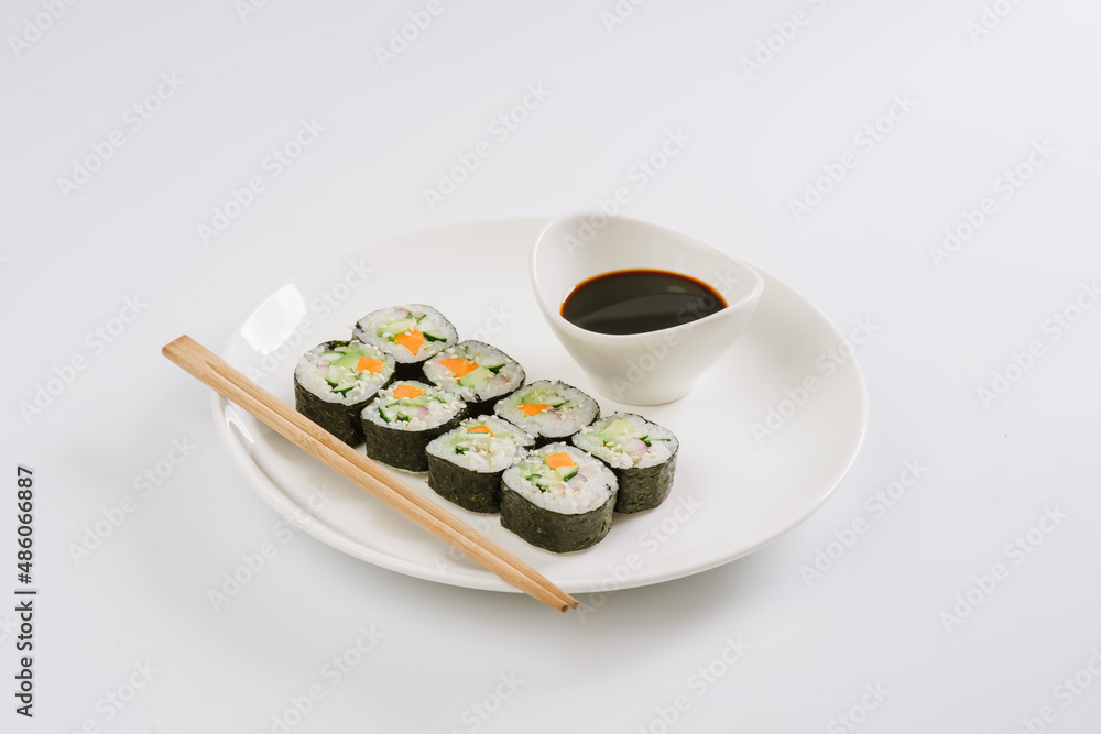 Sushi with chopsticks on a white plate. Sushi roll japanese food in restaurant isolated on white background. Fresh hosomaki pieces with rice and nori. Sushi with chopsticks on a white plate. Sushi roll japanese food in restaurant isolated on white background. Fresh hosomaki pieces with rice and nori.