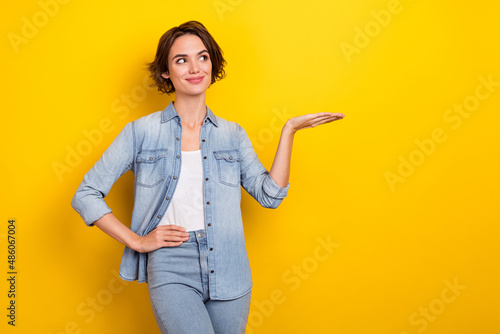 Photo of young woman demonstrate promo ads suggest advertise look empty space isolated over yellow color background