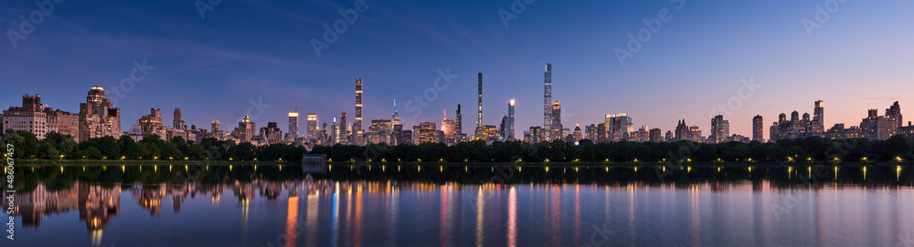 Panoramic New York City skyline. Midtown Manhattan skyscrapers from Central Park Reservoir at Dusk. Evening view of billionaires' row super tall luxury buildings