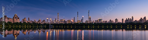 Panoramic New York City skyline. Midtown Manhattan skyscrapers from Central Park Reservoir at Dusk. Evening view of billionaires  row super tall luxury buildings
