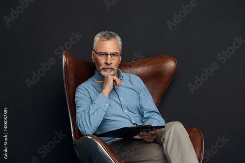 Thoughtful man sit in armchair and look at camera © Drobot Dean