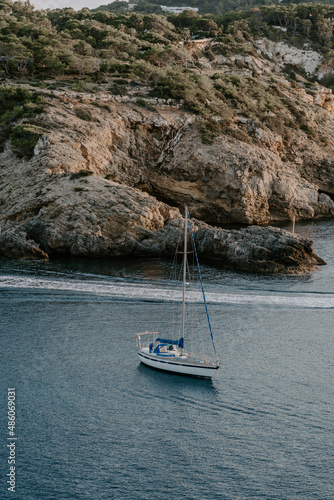 Boat docked by the sea in Ibiza. Overlooking rocky island, houses, sunrise, calm sea
