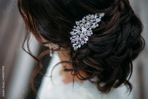 woman's crystal hairpin on the bride's wedding hairstyle with dark hair. hairstyle like a loose bun. soft curls are gathered in a bun photo