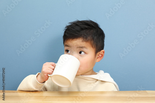 マグカップでドリンクを飲んでいる男の子。