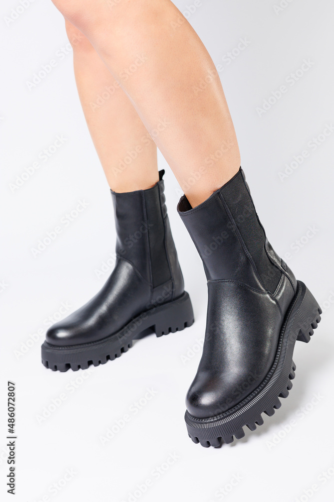 Women's black spring boots made of genuine leather are dressed on bare feet Women's black spring boots made of genuine leather are dressed on bare feet