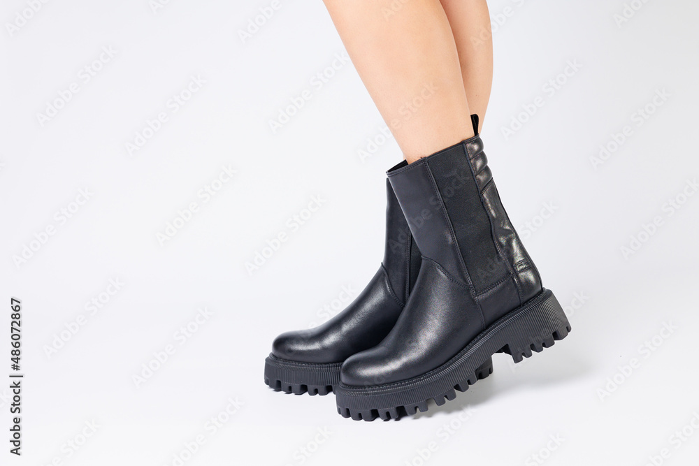 Women's black spring boots made of genuine leather are dressed on bare feet Women's black spring boots made of genuine leather are dressed on bare feet
