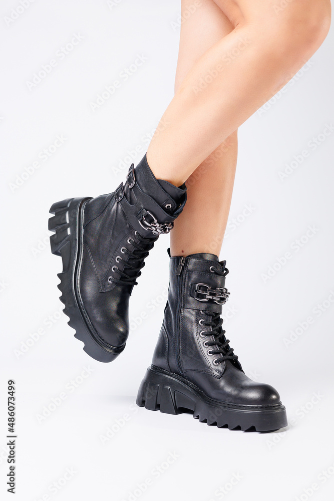 Legs of a woman in black leather boots from a new collection on a white background, legs of a girl in fashionable leather boots spring 2022. Legs of a woman in black leather boots from a new collection on a white background, legs of a girl in fashionable leather boots spring 2022.