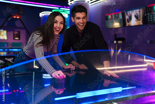 White young friends laughing while playing air hockey © Drobot Dean