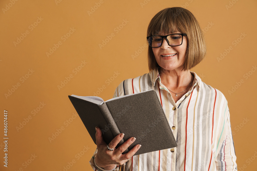 Senior woman wearing eyeglasses smiling while posing with planner Senior woman wearing eyeglasses smiling while posing with planner