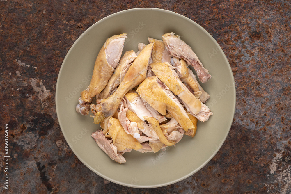 cut of boiled chicken in simply ceramic plate on rusty texture background, top view, flat lay cut of boiled chicken in simply ceramic plate on rusty texture background, top view, flat lay