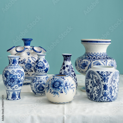 Stillife of natural light and old Dutch Delft blue lidded vases  in the background on white blue linen against a blue background