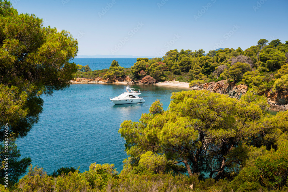 Panoramic photo of turquoise water with a luxury yacht docked in a beautiful bay on a sunny day in Greece